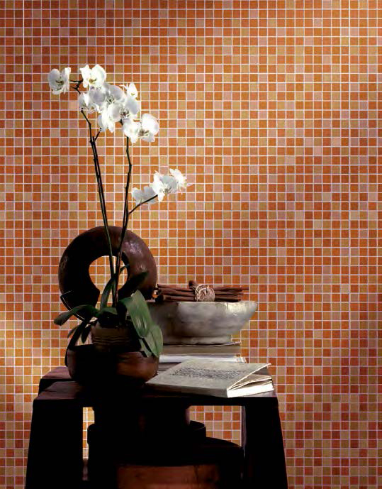 Eine Wand mit lebendigen orangefarbenen Mosaikfliesen, die einen warmen und einladenden Akzent setzen. Vor der Wand befindet sich ein minimalistischer Holzbeistelltisch, dekoriert mit einer weißen Orchidee in einer modernen Vase, einer rustikalen Schale mit dekorativen Zweigen und einem aufgeschlagenen Buch. Die Kombination aus natürlichen und modernen Elementen verleiht dem Raum eine harmonische und inspirierende Atmosphäre. Perfekt für eine stilvolle Raumgestaltung in Wohn- oder Wellnessbereichen.